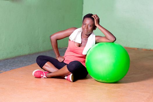 Young woman sitting and arms on a ball to do fitness exercises.