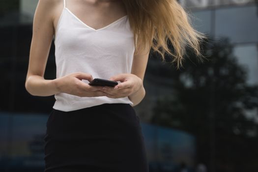 A portrait of a beautiful woman texting a message or reading white standing on a street