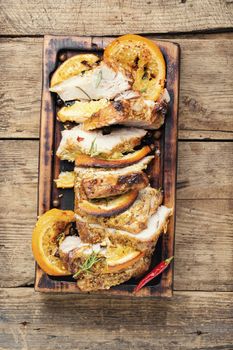 Sliced pork meat stuffed with oranges.Roasted meat on the kitchen board.