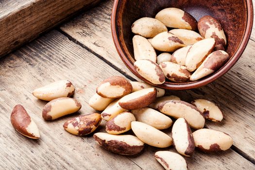 Tasty peeled brazil nut in bowl on old wooden table