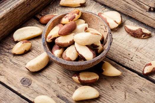 Tasty peeled brazil nut in bowl on old wooden table