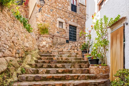 Spain, Tossa de Mar, cobbled street, staircase and stone wall in medieval Old Town - Vila Vella.