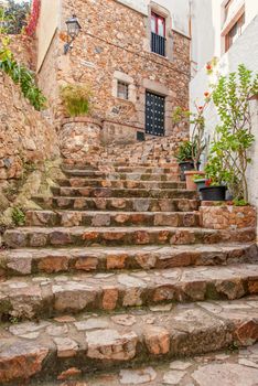 Spain, Tossa de Mar, cobbled street, staircase and stone wall in medieval Old Town - Vila Vella.