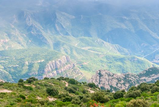 Hazy unusual mountains with green trees and cloudy sky near Montserrat Monastery,Spain. Catalonia