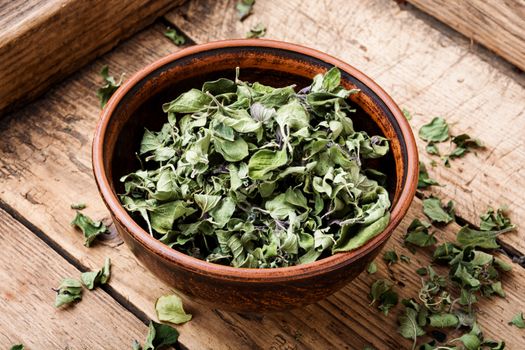 Bowl of dried oregano leaves on wooden background.Oregano or marjoram leaves