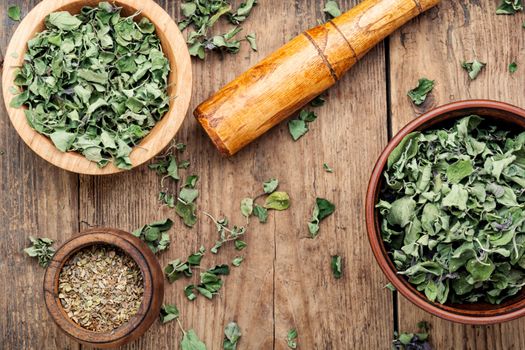 Bowl with dried oregano on old wooden table