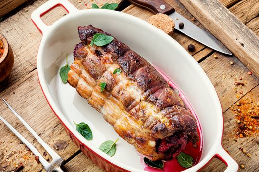 Baked pork meat stuffed cherries.Baked pork on a wooden retro tray