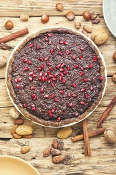 Tasty chocolate cake with pomegranate on wooden background.