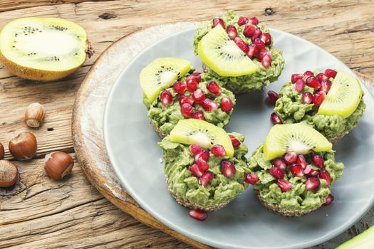 Diet avocado cupcakes garnished with kiwi and pomegranate.Cupcakes on wooden background