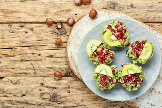 Diet avocado cupcakes garnished with kiwi and pomegranate.Cupcakes on wooden background