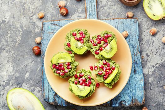 Diet avocado cupcakes garnished with kiwi and pomegranate.American fairy cake
