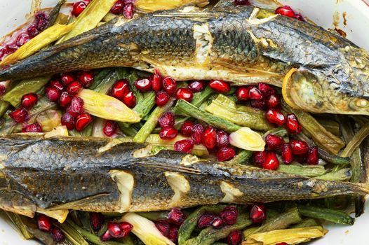 Pelengas baked with vegetables and pomegranateRoasted fish in a baking dish.Healthy food