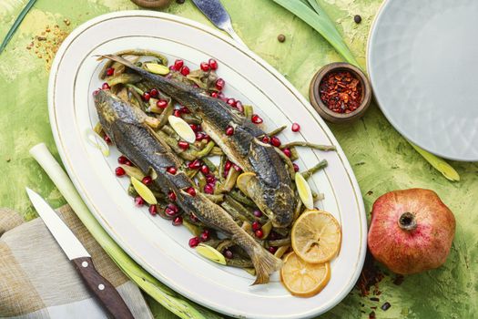 Pelengas baked with vegetables and pomegranate.Cooked roasted fish on plate