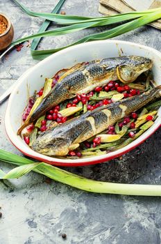 Pelengas baked with vegetables and pomegranate.Cooked roasted fish in a baking dish.