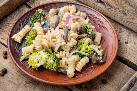 Baked broccoli and pasta with mushrooms.Vegetarian vegetable pasta wooden table.