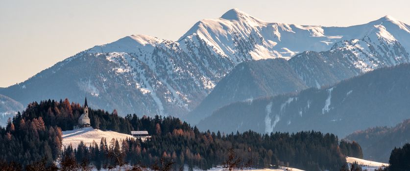 Mountain landscape, picturesque mountain church in the winter morning, large panorama .