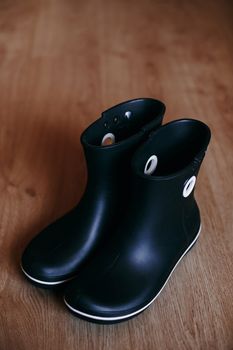 Black rubber boots isolated on wooden background.