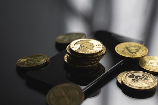 Stack of golden Titan bitcoin coin on a smartphone with a lot of bitcoins coins on a table. Virtual cryptocurrency concept. Mining of bitcoins online bussiness. Bitcoins trading