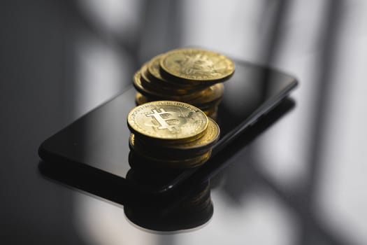 Two stacks of golden bitcoin coin on a smartphone on a table. Virtual cryptocurrency concept. Mining of bitcoins online business. Bitcoins trading