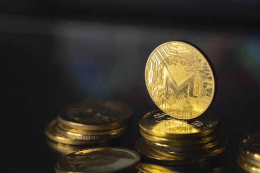 Monero and virtual money concept. Gold monero bitcoins on a stack of coins with chart of growing and falling valuance of a cryptocurrency. Mining or blockchain technology