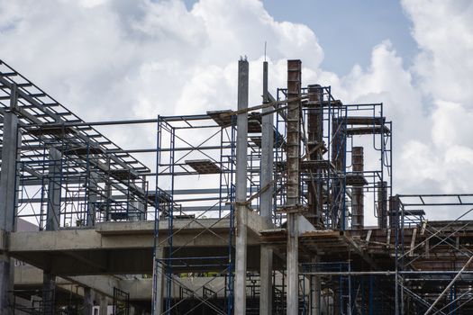 Building and Construction Site in progress. Building construction site against cloudy sky. Metal construction of unfinished building on construction of multi storage building