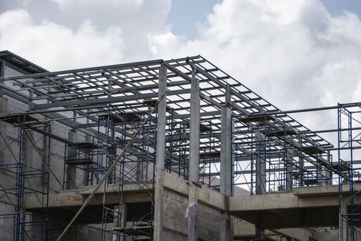 Building and Construction Site in progress. Building construction site against cloudy sky. Metal construction of unfinished building on construction of multi storage building