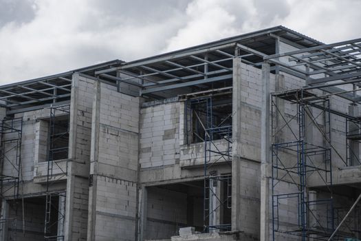 Building and Construction Site in progress. Building construction site against cloudy sky. Metal construction of unfinished building on construction of multi storage building