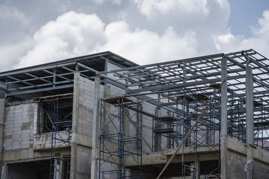 Building and Construction Site in progress. Building construction site against cloudy sky. Metal construction of unfinished building on construction of multi storage building