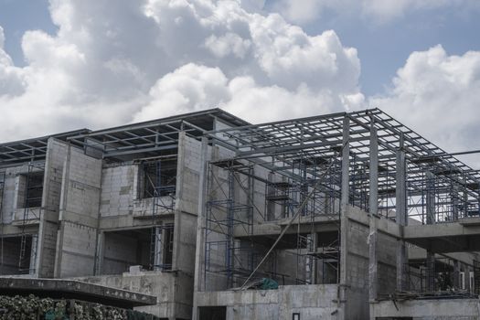 Building and Construction Site in progress. Building construction site against cloudy sky. Metal construction of unfinished building on construction of multi storage building