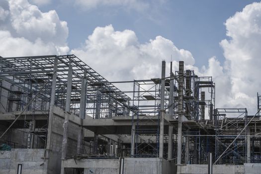 Building and Construction Site in progress. Building construction site against cloudy sky. Metal construction of unfinished building on construction of multi storage building