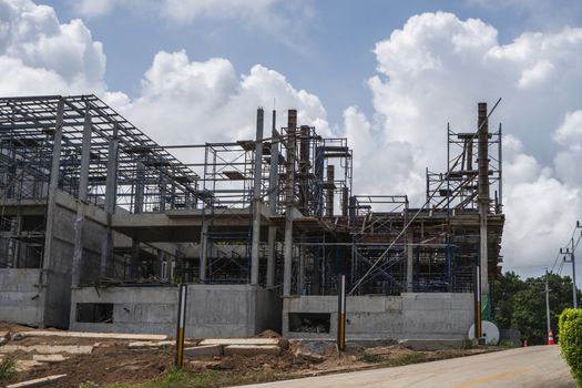 Building and Construction Site in progress. Building construction site against cloudy sky. Metal construction of unfinished building on construction of multi storage building