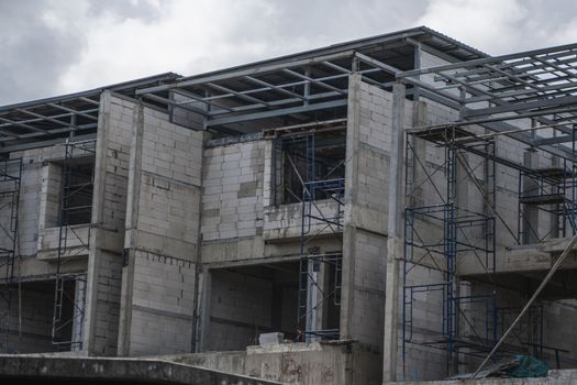 Building and Construction Site in progress. Building construction site against cloudy sky. Metal construction of unfinished building on construction of multi storage building