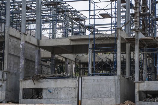 Building and Construction Site in progress. Building construction site against cloudy sky. Metal construction of unfinished building on construction of multi storage building