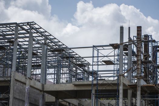 Building and Construction Site in progress. Building construction site against cloudy sky. Metal construction of unfinished building on construction of multi storage building