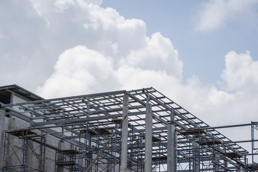 Building and Construction Site in progress. Building construction site against cloudy sky. Metal construction of unfinished building on construction of multi storage building