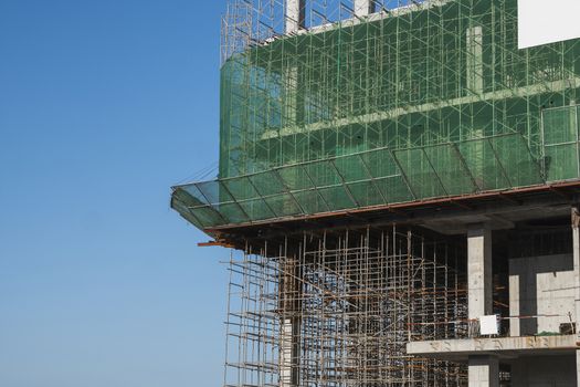 Building and Construction Site in progress. Building construction site against blue sky. Metal construction of unfinished building on construction of multi storage building