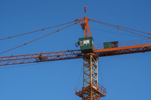 Tower crane against blue sky on a construction site for building of multi storage building or another type of structure