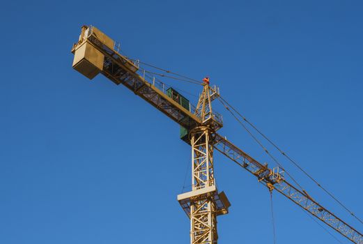 Tower crane against blue sky on a construction site for building of multi storage building or another type of structure