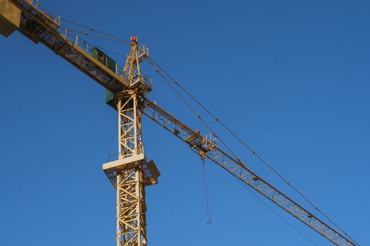 Tower crane against blue sky on a construction site for building of multi storage building or another type of structure