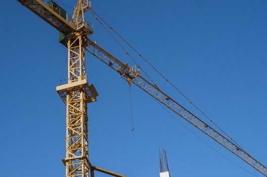 Tower crane against blue sky on a construction site for building of multi storage building or another type of structure