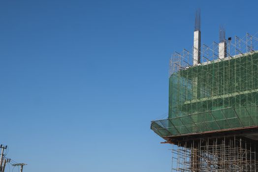 Building and Construction Site in progress. Building construction site against blue sky. Metal construction of unfinished building on construction of multi storage building