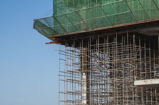 Building and Construction Site in progress. Building construction site against blue sky. Metal construction of unfinished building on construction of multi storage building