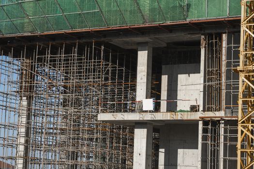 Building and Construction Site in progress. Building construction site against blue sky. Metal construction of unfinished building on construction of multi storage building