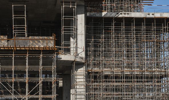 Building and Construction Site in progress. Building construction site against blue sky. Metal construction of unfinished building on construction of multi storage building