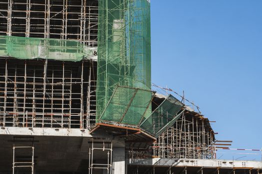 Building and Construction Site in progress. Building construction site against blue sky. Metal construction of unfinished building on construction of multi storage building