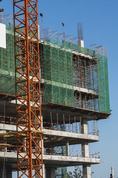 Crane and building construction site against blue sky. Metal construction of unfinished building on construction. Tower Crane use for building of multi storage building