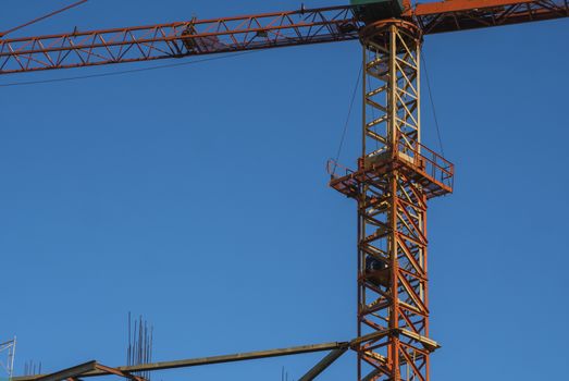 Tower crane against blue sky on a construction site for building of multi storage building or another type of structure