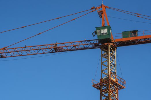 Tower crane against blue sky on a construction site for building of multi storage building or another type of structure