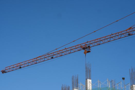 Tower crane against blue sky on a construction site for building of multi storage building or another type of structure