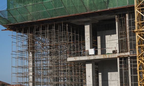 Building and Construction Site in progress. Building construction site against blue sky. Metal construction of unfinished building on construction of multi storage building